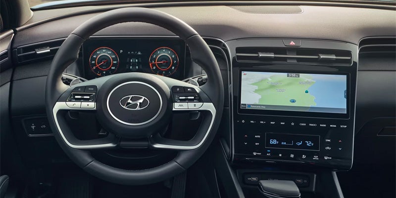 The dashboard of a car, showing the steering wheel, digital instrument cluster, and infotainment system with a map.