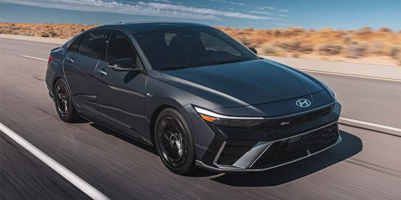 A Black Hyundai Elantra sedan parked on a city street at sunset