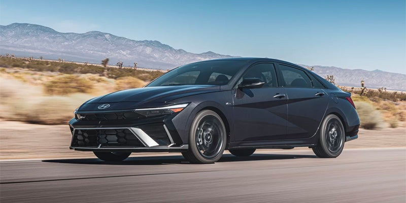 Hyundai Elantra on a desert road with mountains in the background.