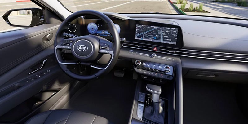 Interior of a car showing the dashboard, steering wheel, infotainment screen, and gear shift.