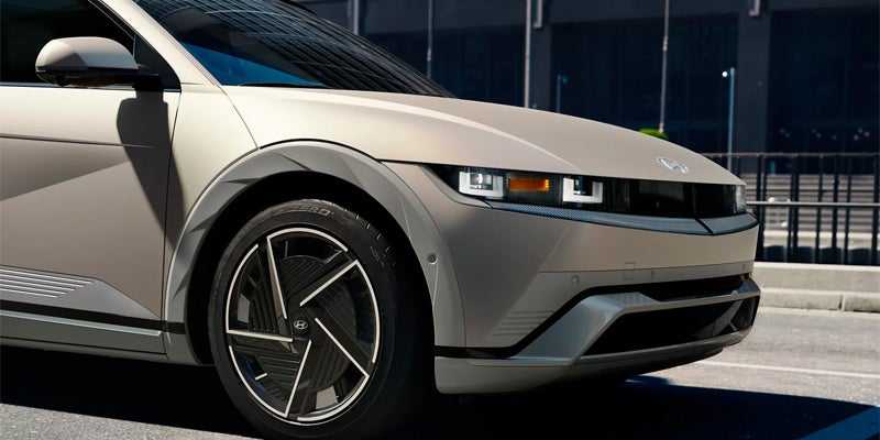 Front side close-up of a modern, tan-colored car with angular features.