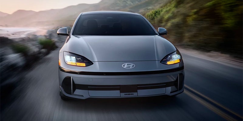 Front view of a Hyundai Ioniq 6 driving on a coastal road at dusk.