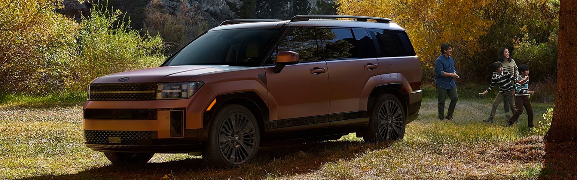 SUV parked in a grassy forest with a family playing nearby.
