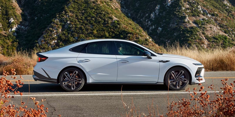 A Hyundai Sonata is parked on the side of a road, with mountains and dry vegetation in the background.