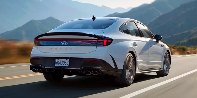 Rear view of a Hyundai Sonata driving on a mountain road.
